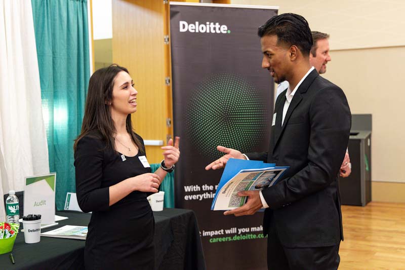 Photo of a Deloitte recruiter speaking with a UNT student.